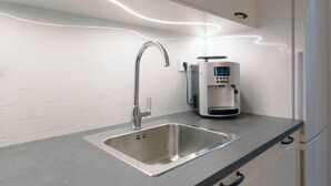 A modern kitchen with a stainless steel sink, a kettle, and a sleek countertop.
