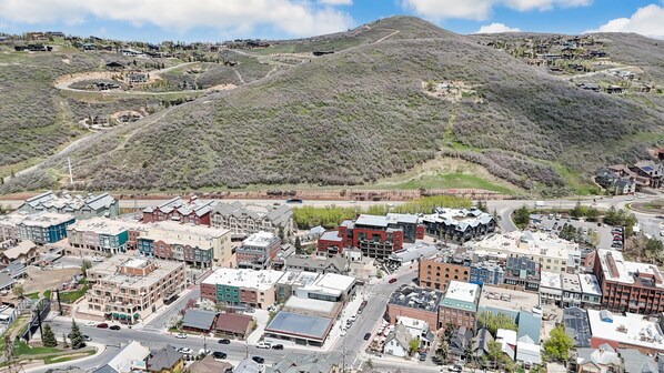 Un pueblo con una mezcla de edificios modernos y tradicionales, una calle principal y montañas al fondo.