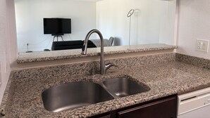 Cuina amb encimera de granat, rentapelats d'acer inoxidable i armaris de fusta.