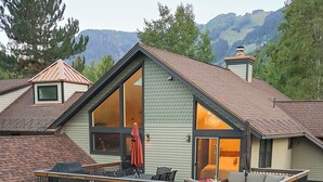 Una casa a due piani con un balcone, un portico coperto e vista sulle montagne.