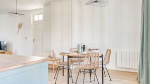A modern dining area with a round table, wicker chairs, and pendant lighting.