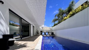 A modern outdoor pool area with a clear blue mosaic tile border, a patio with stone tiles, and a white wall with a vertical garden. - Villa do Mar - Close to the beach (Aroeira)