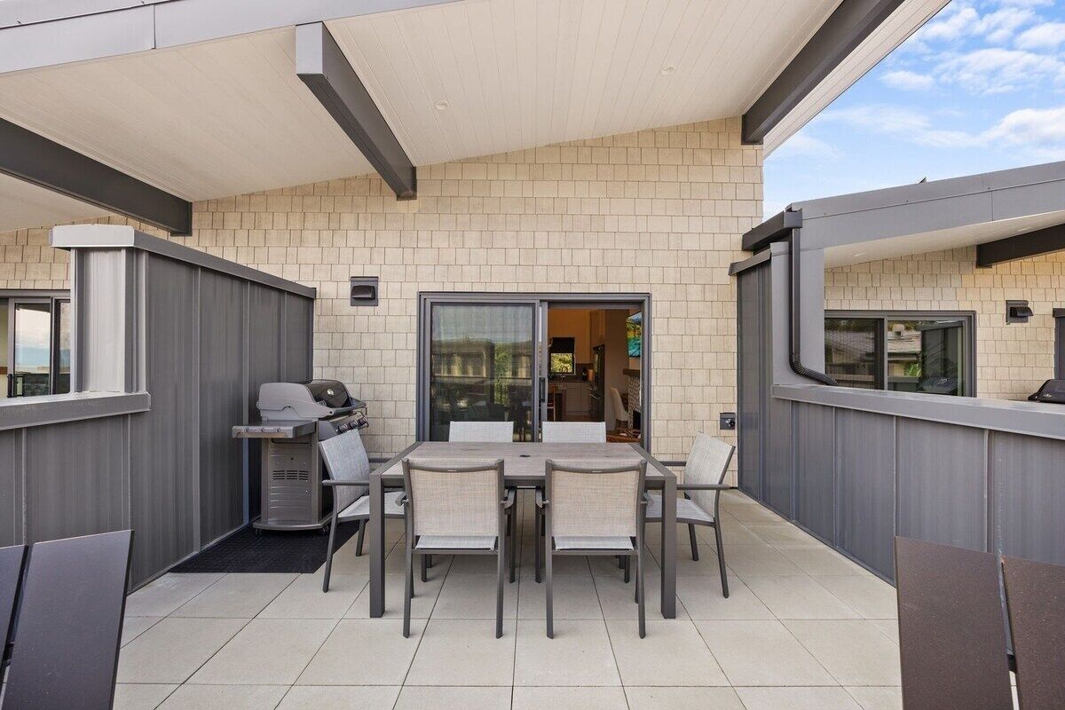 An outdoor patio with a grill, dining table, and chairs.
