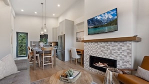 Una sala de estar moderna con chimenea, un comedor y una cocina.