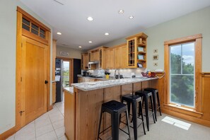 A kitchen with wooden cabinets, a granite countertop, and a large window.