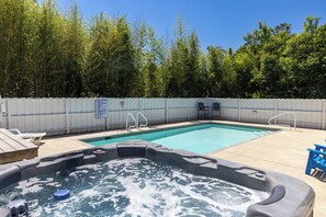 A backyard with a swimming pool, hot tub, and outdoor seating.