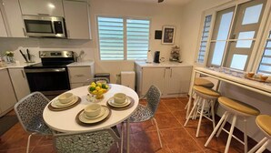 A modern kitchen with white cabinets, a microwave, and a dining area with a round table and chairs. - Stay in the heart of Puerto Rico in a cozy home Casa Juani - Orocovis,PR!  (Orocovis)