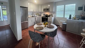 A modern kitchen with white cabinets, stainless steel appliances, and a dining area with a round table and chairs. - Stay in the heart of Puerto Rico in a cozy home Casa Juani - Orocovis,PR!  (Orocovis)
