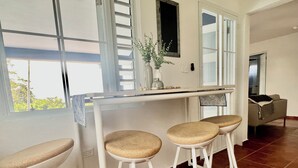 A kitchen with a bar area, a dining table, and a sofa. - Stay in the heart of Puerto Rico in a cozy home Casa Juani - Orocovis,PR!  (Orocovis)
