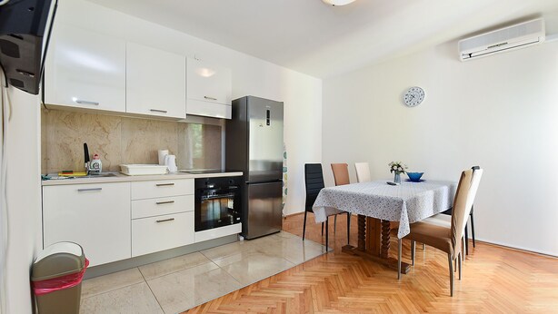 A modern kitchen with white cabinets, a built-in oven, and a dining area with a table and chairs. - Apartment 2362/116995 (Istria - Rovinj), 800m from the beach (Rovinj)