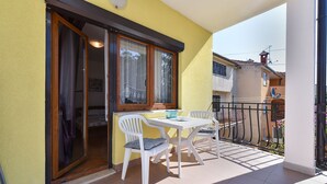 A balcony with a table and chairs, a window with lace curtains, and a door leading to a room. - Apartment 2362/116995 (Istria - Rovinj), 800m from the beach (Rovinj)