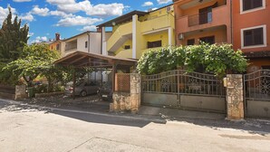 A residential street with colorful houses, a covered carport, and a gated entrance. - Apartment 2362/116995 (Istria - Rovinj), 800m from the beach (Rovinj)
