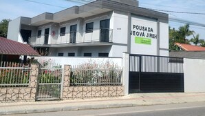 A modern two-story building with a sign reading "Pousada Jeová Jireh". - Pousada da Família com Apartamentos Mobiliados e Completos! (Santa Lidia Penha)