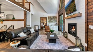 A spacious living room with a fireplace, leather sofa, and a coffee table.