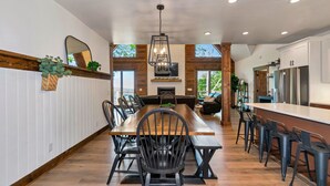A modern kitchen with a central island, wooden flooring, and a large dining table with chairs.