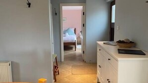 Un corridoio stretto che conduce a una camera da letto con un letto e un comodino.