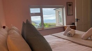 Una camera da letto con un'ampia finestra, un letto con cuscini e un asciugamano sul letto.