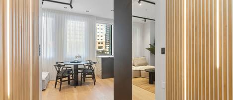 A modern interior with a dining area, a sofa, and a view of a building outside.