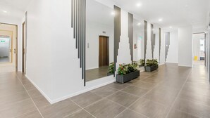 A modern hotel corridor with a long hallway, a reception area, and a visible elevator. - Victoria Street Apartments (Auckland)