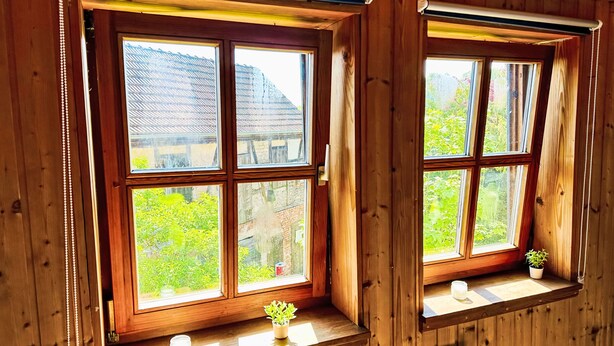 Una cabaña de madera con dos ventanas, cada una con un pequeño estante y una vela.