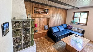 Una sala de estar acogedora con una pared de madera, un sofá de cuero negro, una mesa de centro de madera y un mueble de sonido original.