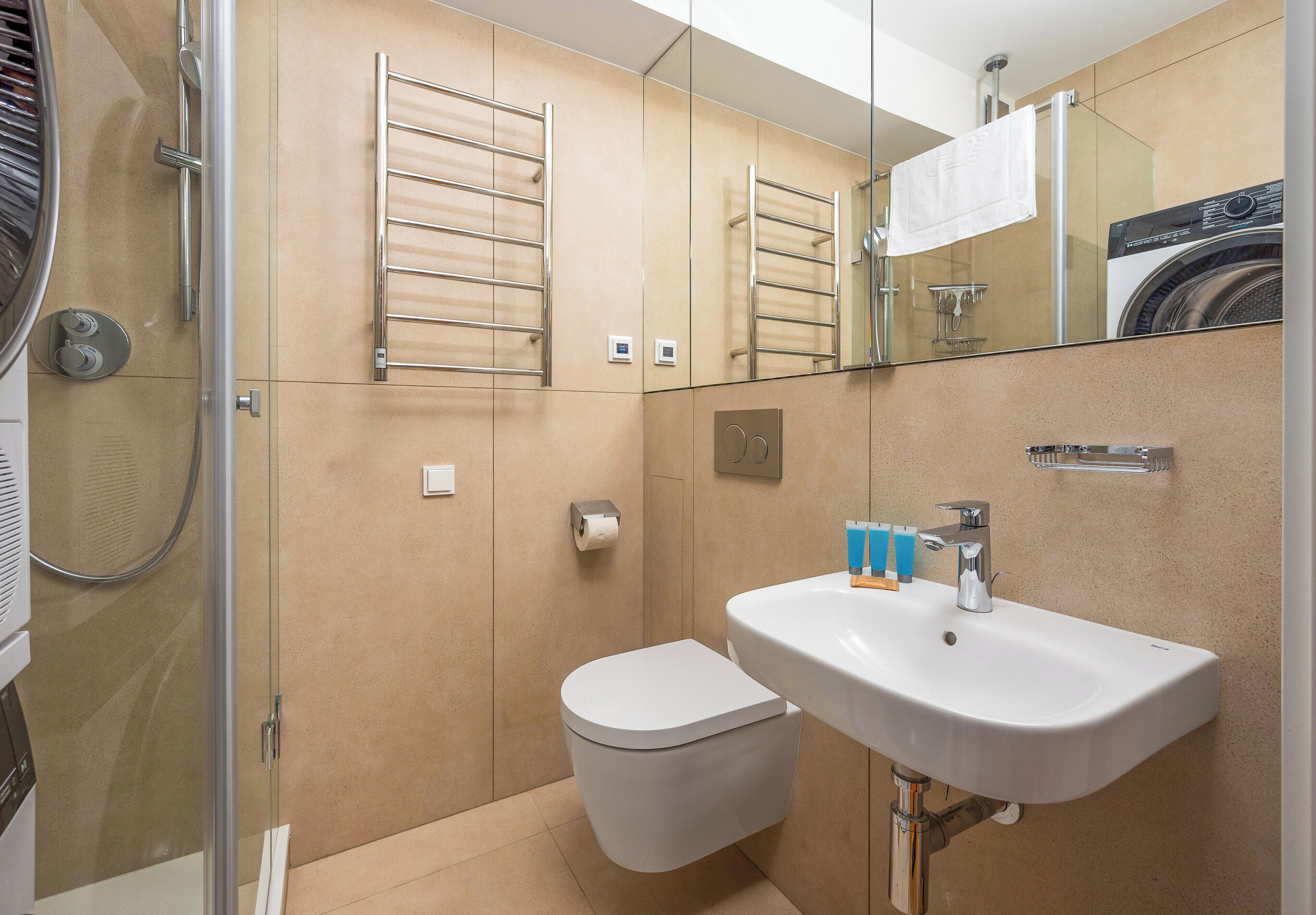 Une salle de bain moderne équipée de toilettes, d’un lavabo et d’une douche à parois en verre.