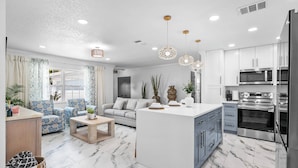 A modern kitchen with white cabinets, a central island, and stainless steel appliances.