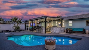 A swimming pool with a covered patio area, a bar, and outdoor seating.