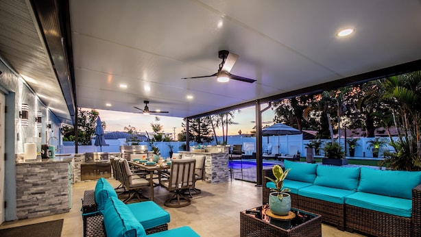 An outdoor living area with a pool, seating, and a bar.