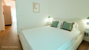 A bedroom with a large bed, two bedside lamps, and a framed picture on the wall. - [Torino Centro] Iliade House (Torino)