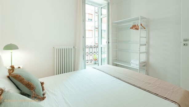 A bedroom with a bed, a wardrobe, a radiator, and a view through an open door to an outdoor balcony. - [Torino Centro] Iliade House (Torino)
