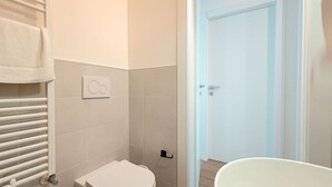 A bathroom with a toilet, a towel rack, and a shower area. - [Torino Centro] Iliade House (Torino)