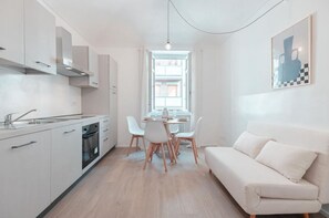 Une cuisine moderne avec des meubles blancs, une table à manger avec des chaises et un canapé blanc.