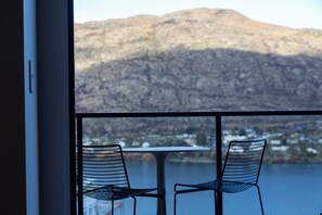 Blick vom Balkon auf eine Berglandschaft mit zwei Stühlen und einem Tisch.