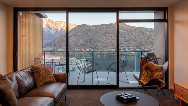 Ein modernes Zimmer mit einer großen Glasschiebetür, die zu einem Balkon mit Bergblick führt.