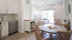 Cozinha moderna com armários brancos, lava-louças e área de refeições com mesa e cadeiras redondas.