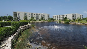 Um hotel moderno com piscina, rodeado por vegetação e um céu limpo.