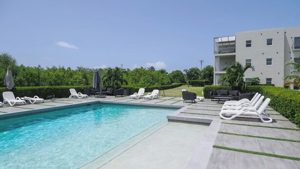 Piscina com espreguiçadeiras e um edifício moderno ao fundo.