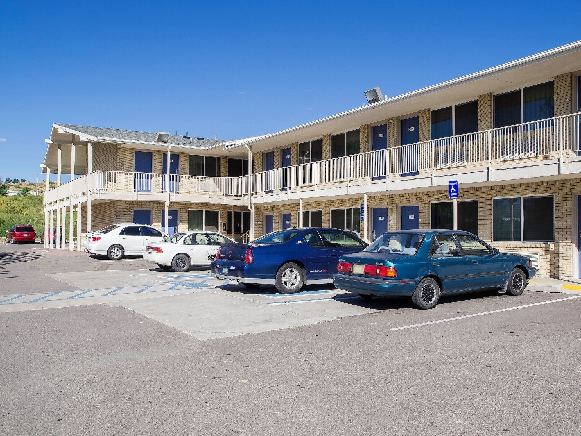 A motel with multiple floors, parking spaces, and a blue handicap parking sign.