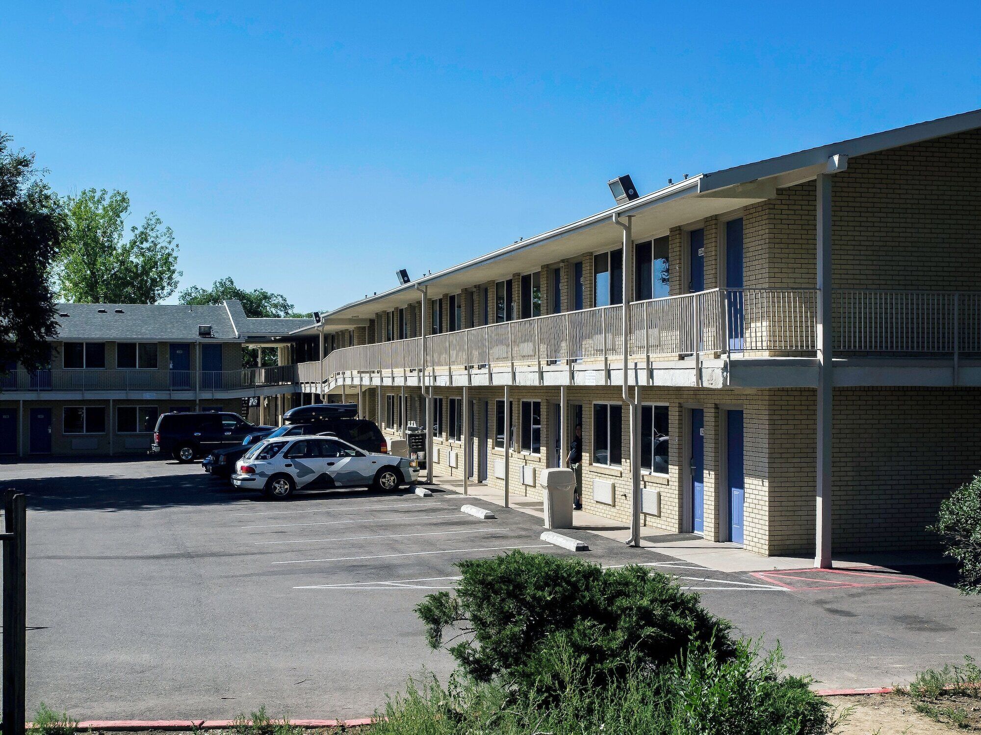 A motel with a two-story structure, a covered parking area, and a visible entrance.