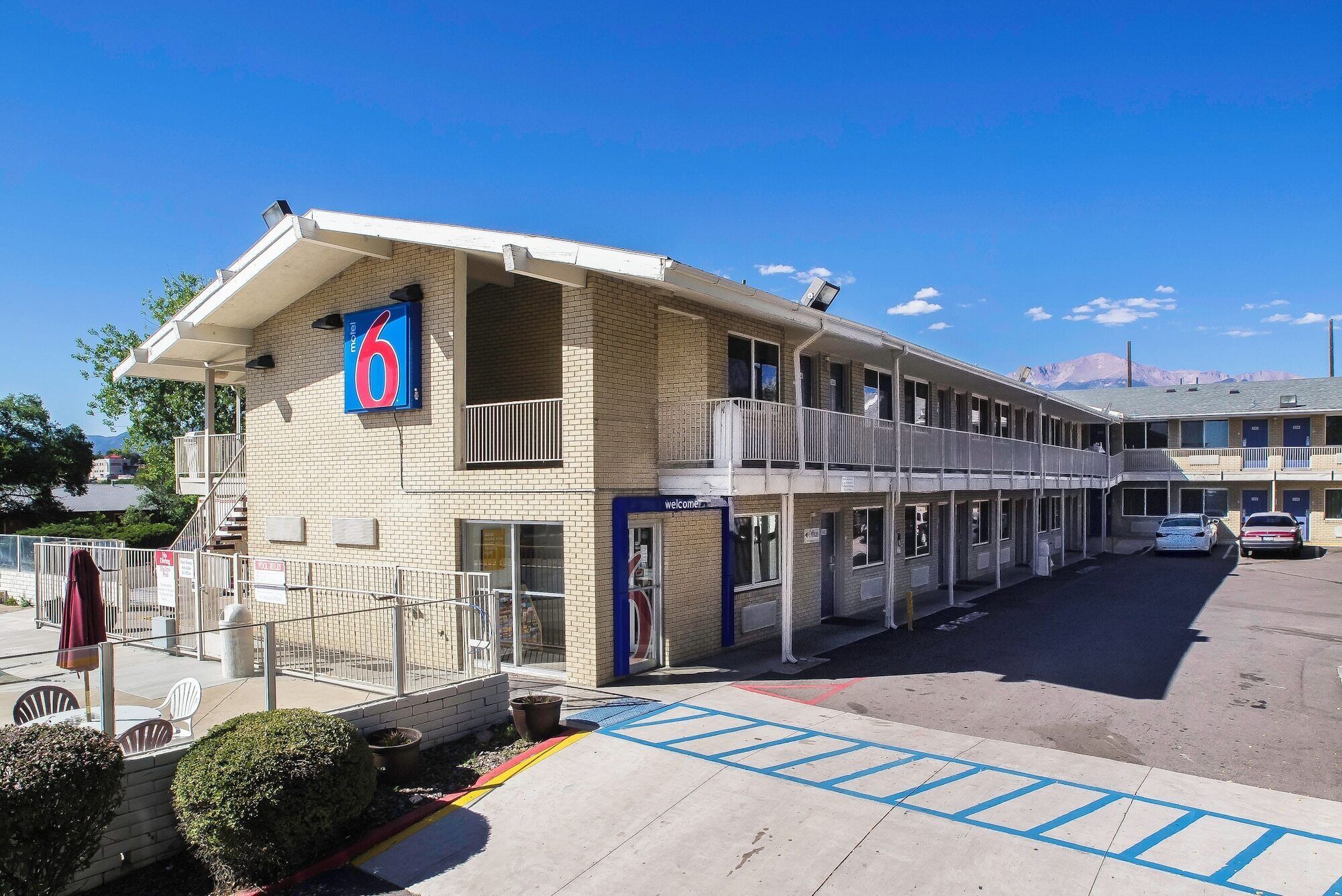 Un motel con una estructura de dos pisos, un balcón en el nivel superior y un estacionamiento al frente.