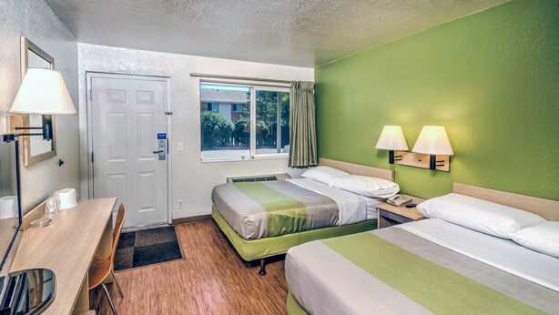 A hotel room with two beds, a desk, a chair, a window, and a door. - Motel 6 – Colorado Springs, CO – South/Metro Area (Colorado Springs)