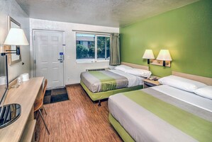 Una habitación de hotel con dos camas, un escritorio, una silla, una ventana y una puerta.