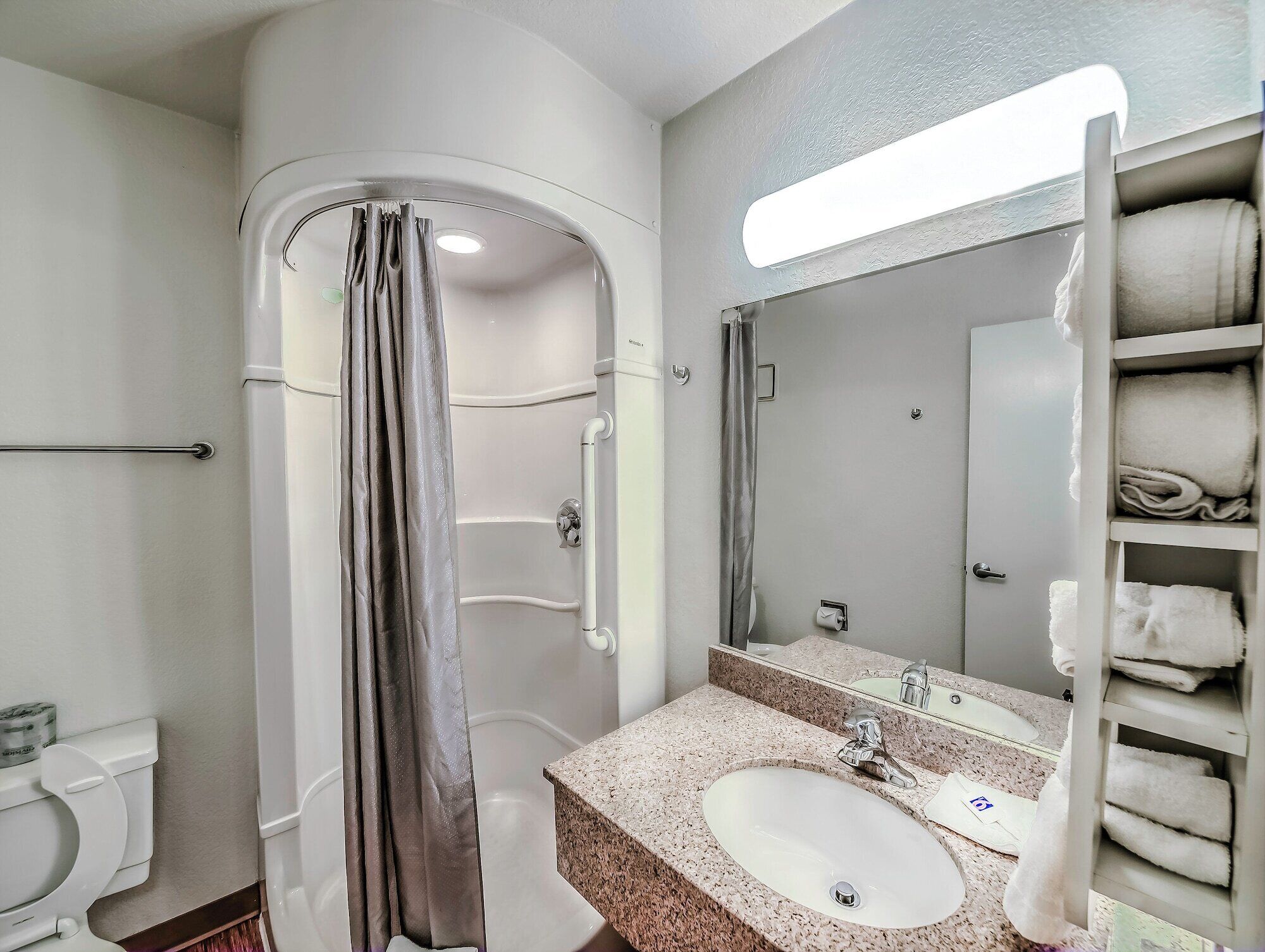 A bathroom with a shower, toilet, sink, and towel rack.