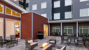 An outdoor patio area with wicker furniture, a fire pit, and a grill. - Residence Inn by Marriott Mechanicsburg (Enola)