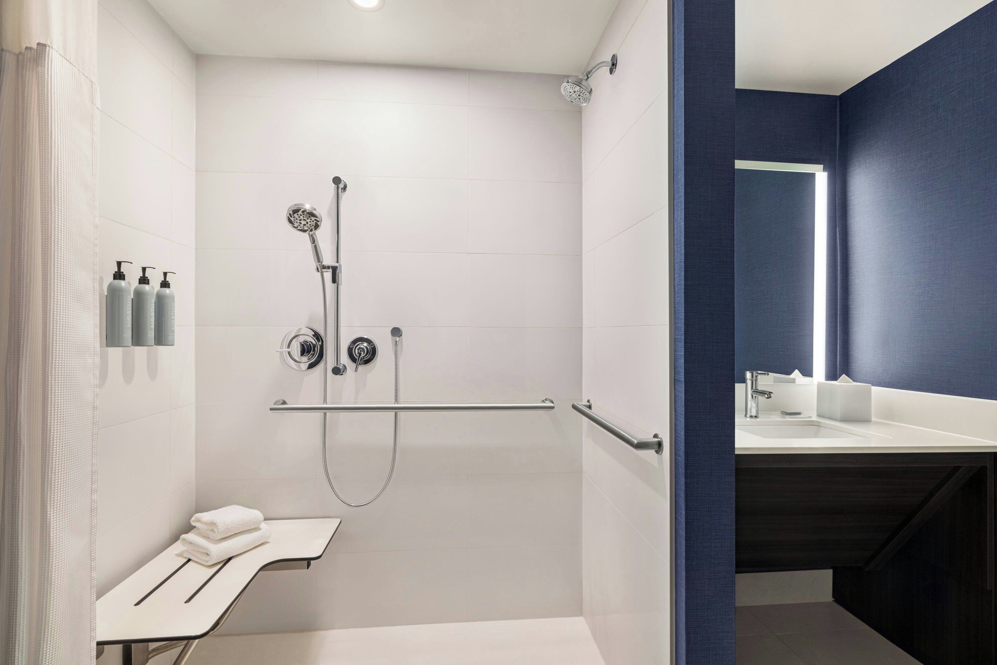 Un baño moderno con cabina de ducha, tocador con lavabo y espejo.
