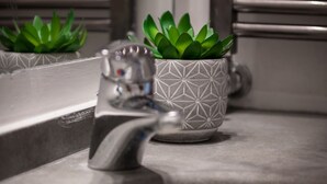 A bathroom sink with a modern faucet and two potted plants. - Rooftop View Bilo - Bocconi Area (Milano)