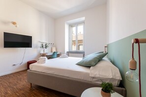 A bedroom with a bed, a desk, a chair, a TV mounted on the wall, and a window. - Rooftop View Bilo - Bocconi Area (Milano)