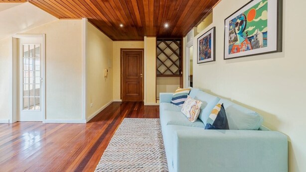 A living room with a wooden ceiling, a light blue sofa, and a patterned rug. - Setúbal Downtown Nº97B (Setúbal)