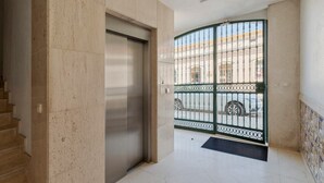 A hallway with a closed elevator, a gated entrance, and a tiled floor. - Setúbal Downtown Nº97B (Setúbal)